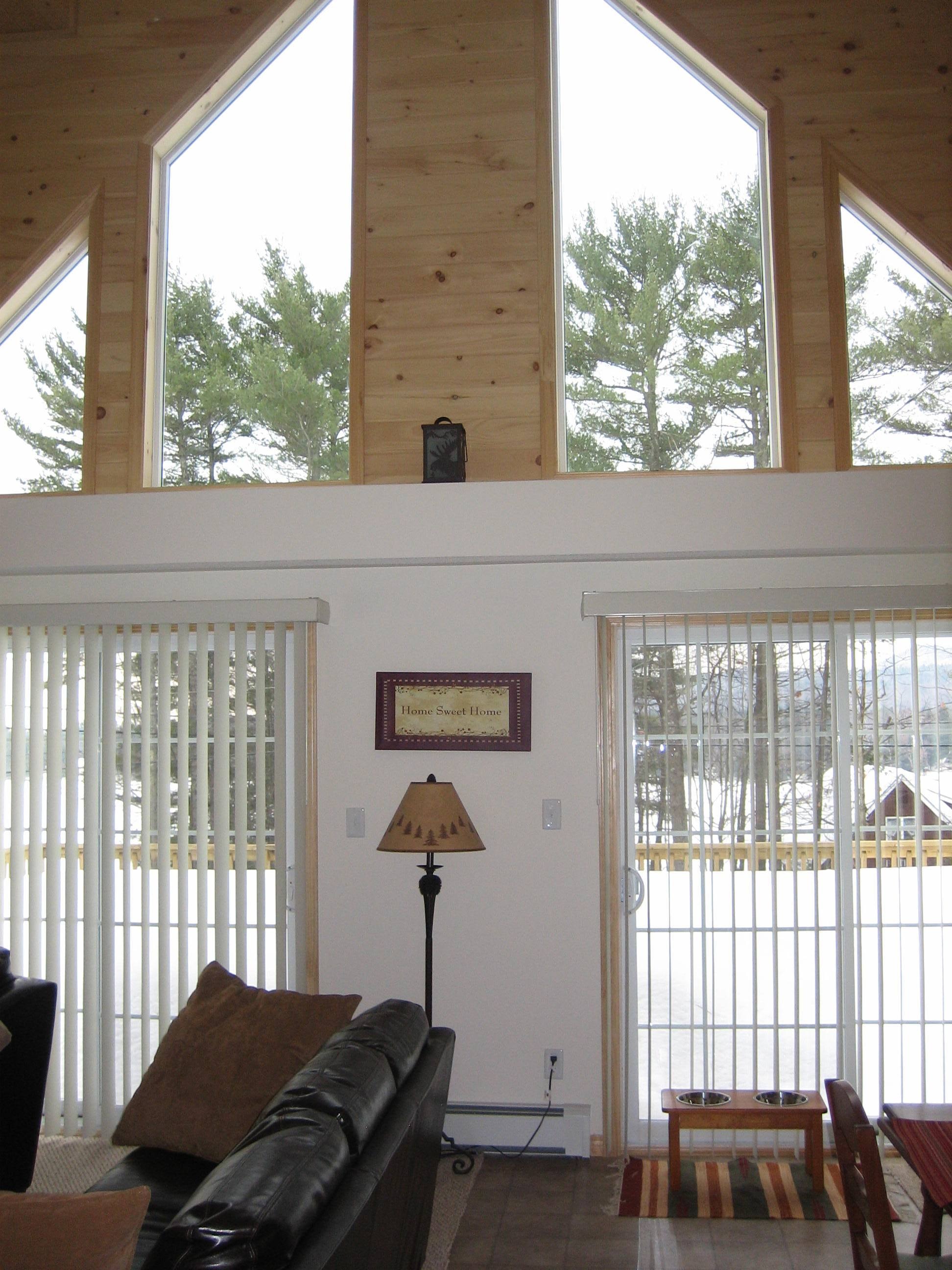 Thompson living room with vaulted wood ceiling and tall windows